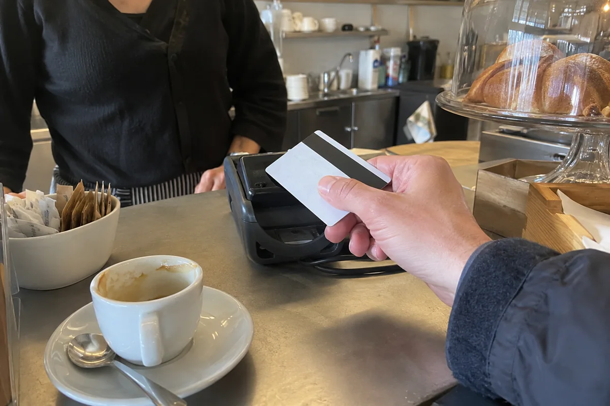 Kontaktlos mit Karte an einer Cafétheke bezahlen